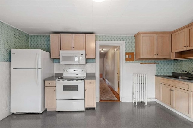 kitchen featuring a sink, white appliances, wallpapered walls, and a wainscoted wall