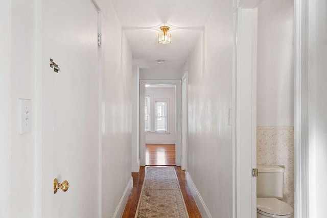 corridor featuring wood finished floors and baseboards