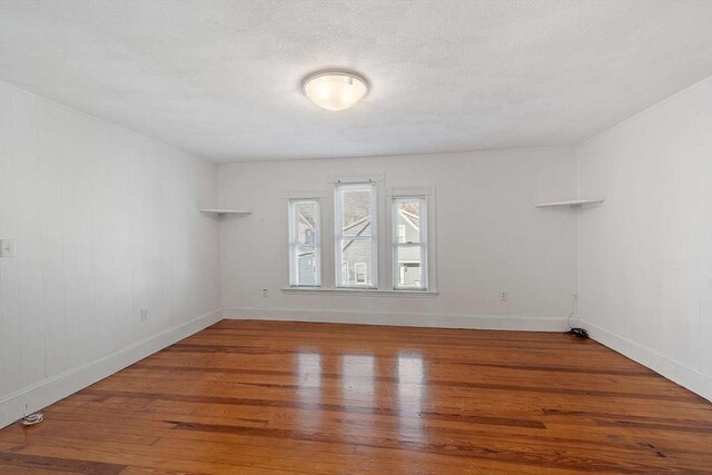 unfurnished room featuring a textured ceiling, baseboards, and wood finished floors