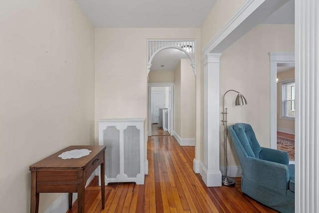 corridor featuring hardwood / wood-style floors, decorative columns, and baseboards