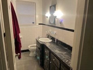 bathroom featuring tile patterned floors, vanity, toilet, and tile walls