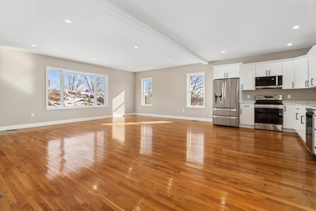 unfurnished living room with beam ceiling and light hardwood / wood-style floors