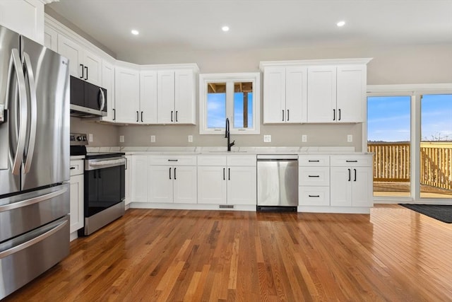 kitchen featuring white cabinetry, appliances with stainless steel finishes, dark hardwood / wood-style floors, and sink