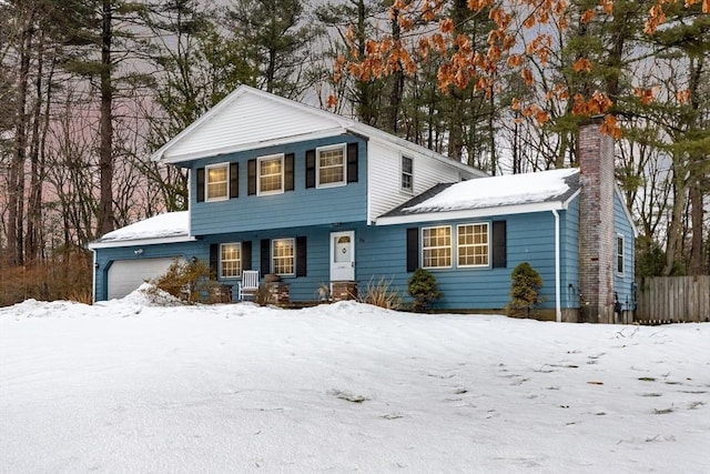 view of front of home with a garage, a chimney, and fence