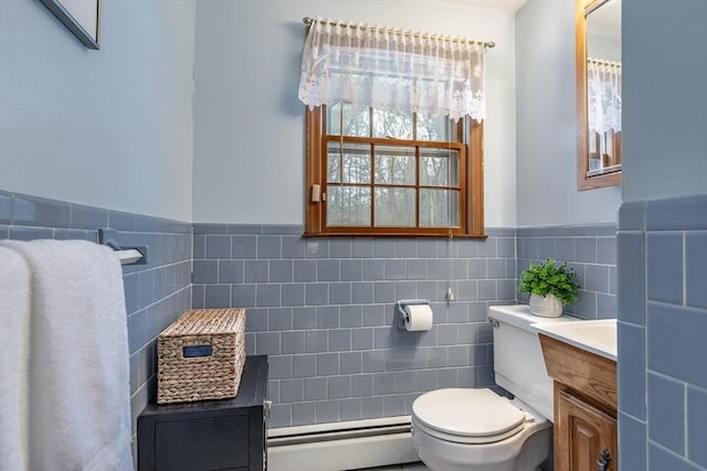 bathroom with tile walls, toilet, a baseboard heating unit, wainscoting, and vanity