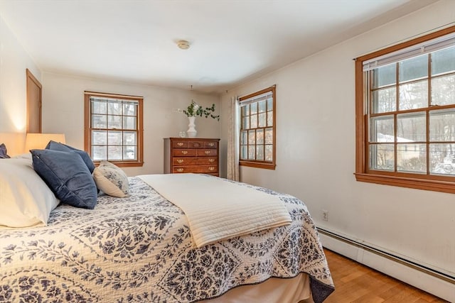 bedroom with a baseboard radiator and light wood finished floors