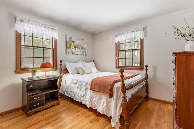 bedroom with light wood finished floors, multiple windows, and baseboards