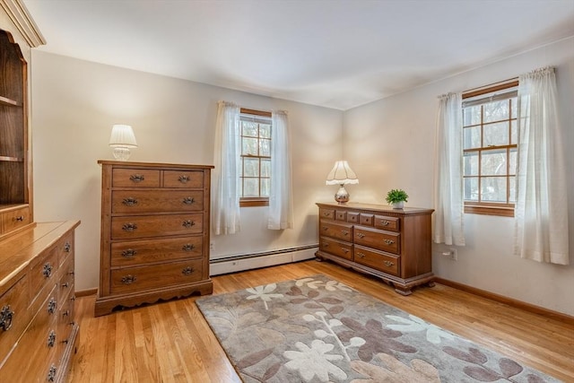 living area with baseboards, baseboard heating, and light wood-style floors