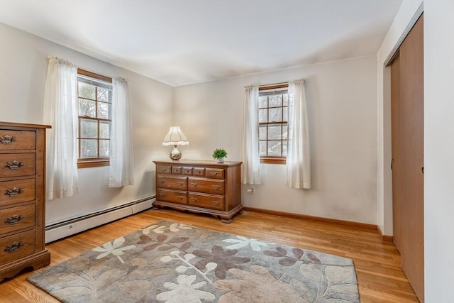 sitting room featuring light wood-style flooring, a baseboard heating unit, and a wealth of natural light