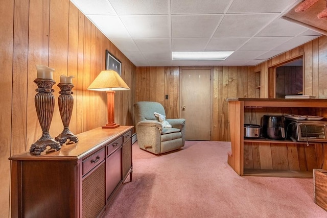 sitting room featuring carpet floors, a drop ceiling, and wood walls