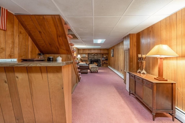 bar featuring wood walls, a warm lit fireplace, a baseboard heating unit, and carpet flooring