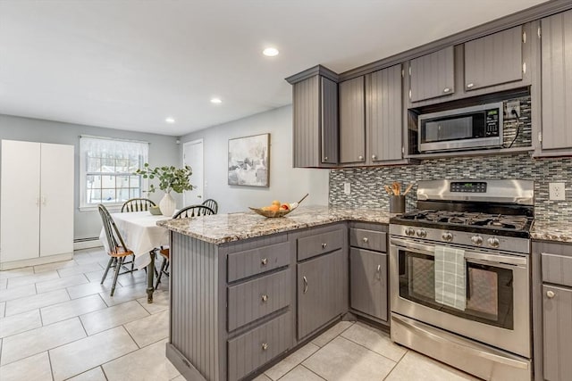 kitchen with stainless steel appliances, a peninsula, gray cabinetry, and tasteful backsplash