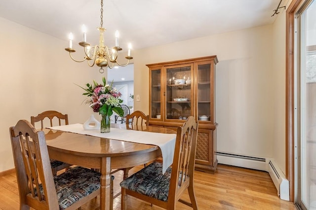 dining area featuring light wood-style flooring, baseboard heating, and a notable chandelier