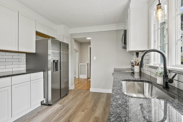 112 Brookline St, Worcester, MA 01603 - kitchen featuring appliances with stainless steel finishes, white cabinetry, dark stone countertops, light wood-style flooring, and decorative backsplash