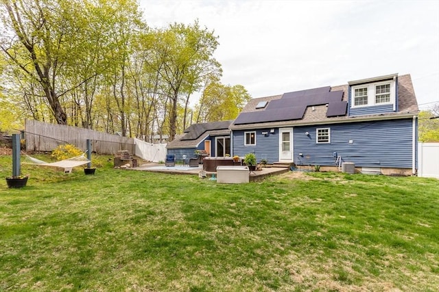 back of house with a patio, a fenced backyard, an outdoor living space, a lawn, and solar panels