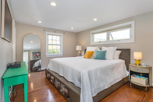 bedroom featuring wood-type flooring, arched walkways, recessed lighting, and multiple windows