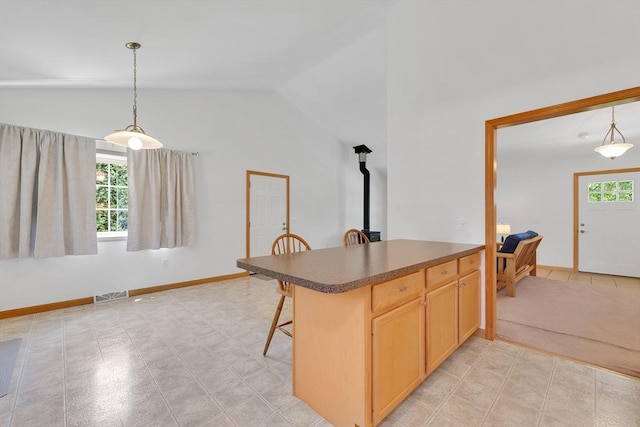 16 Amherst St, Chicopee, MA 01013 - kitchen with vaulted ceiling, a wood stove, dark countertops, pendant lighting, and a kitchen bar