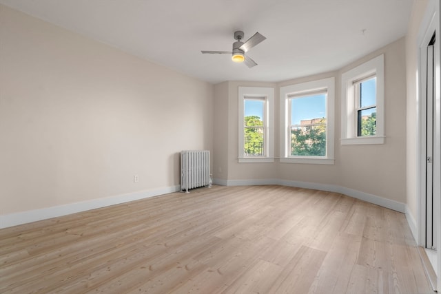 unfurnished room with radiator heating unit, light hardwood / wood-style floors, and ceiling fan