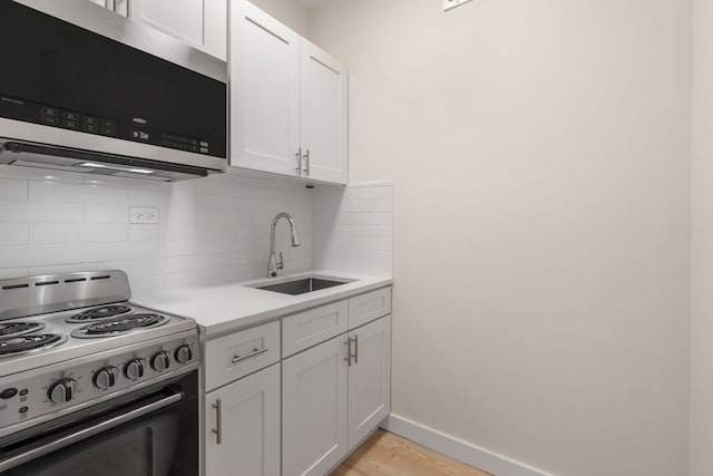 kitchen with white cabinets, sink, tasteful backsplash, range with electric cooktop, and light hardwood / wood-style floors