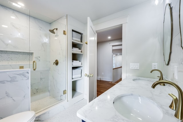 bathroom featuring double vanity, toilet, a shower with shower door, and hardwood / wood-style flooring