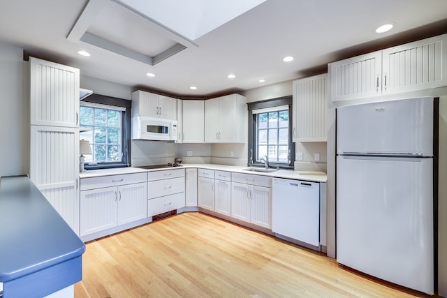 kitchen with a healthy amount of sunlight, light wood-type flooring, white appliances, and white cabinetry