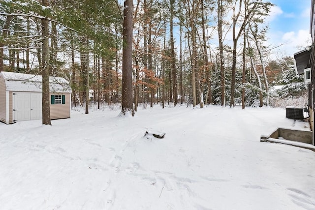 yard layered in snow featuring a storage unit and central AC