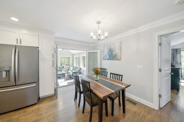 dining space with hardwood / wood-style flooring, crown molding, a notable chandelier, and a wealth of natural light