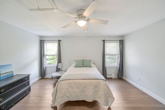 bedroom featuring multiple windows, hardwood / wood-style floors, and ceiling fan