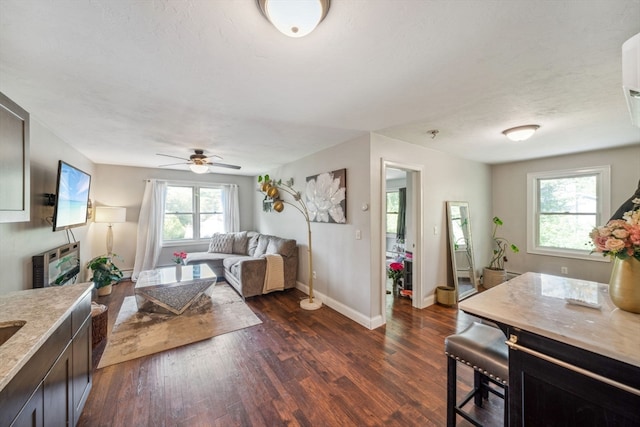 living room with a textured ceiling, dark hardwood / wood-style flooring, ceiling fan, and a wealth of natural light