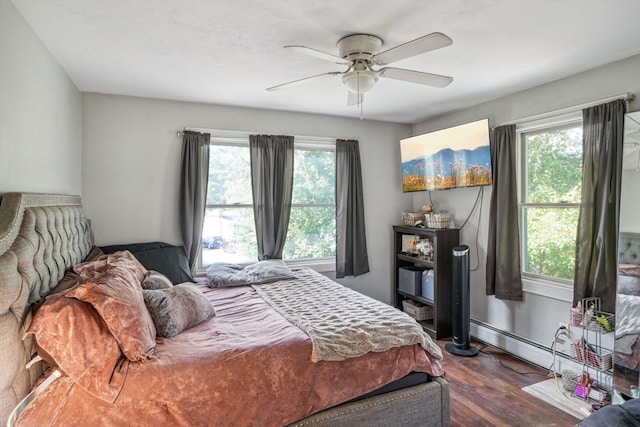 bedroom with ceiling fan, dark hardwood / wood-style flooring, and a baseboard heating unit