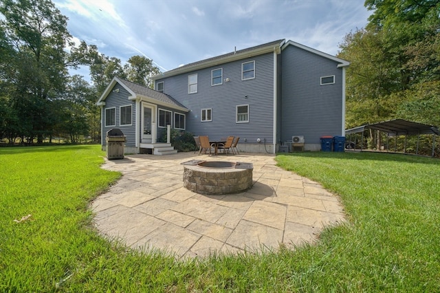 back of property with a carport, a lawn, a patio, and an outdoor fire pit