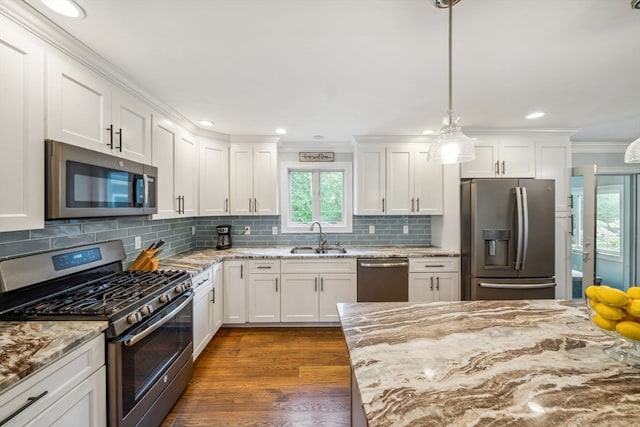 kitchen featuring pendant lighting, stainless steel appliances, white cabinetry, and a wealth of natural light