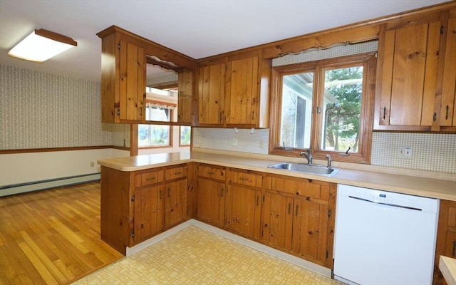 kitchen with white dishwasher, a baseboard radiator, light countertops, brown cabinets, and a sink