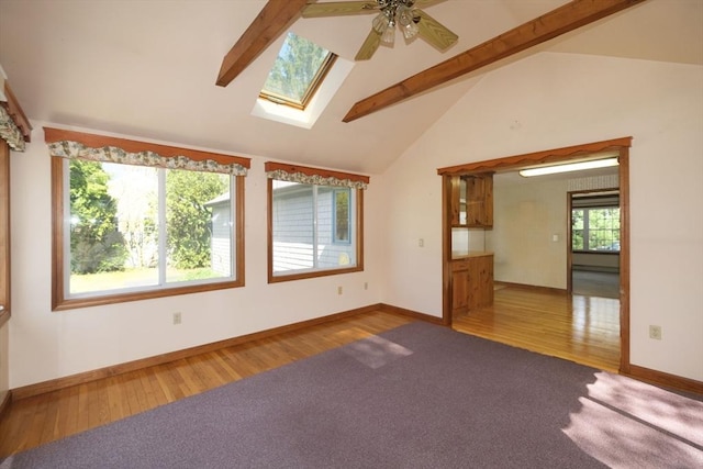 carpeted empty room with baseboards, wood finished floors, and vaulted ceiling with skylight