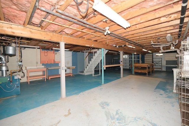 unfinished below grade area featuring a heating unit and stairs