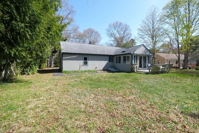 rear view of house featuring a wooden deck, a yard, and a chimney