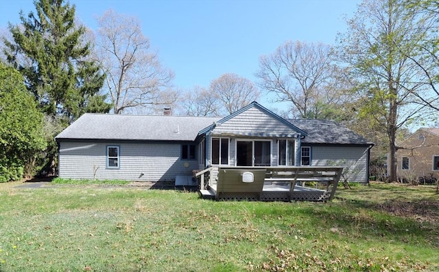 back of house featuring a lawn, a shingled roof, and a wooden deck