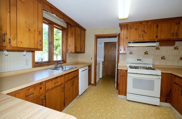 kitchen featuring a sink, light countertops, light floors, under cabinet range hood, and white appliances