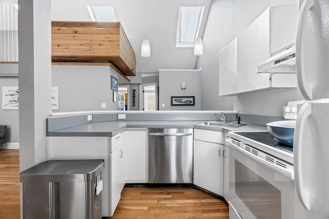 kitchen featuring white appliances, white cabinets, a peninsula, under cabinet range hood, and a sink