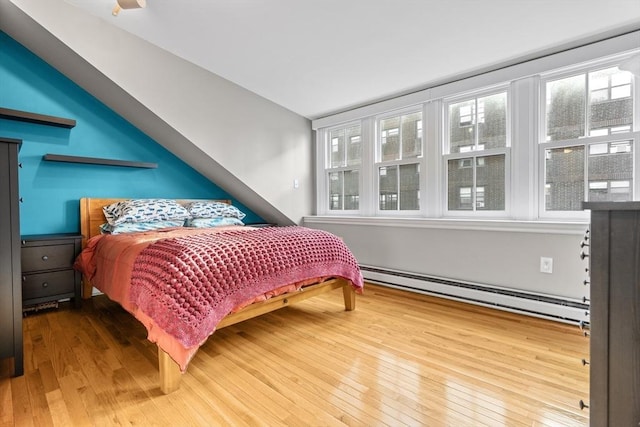 bedroom with a baseboard radiator and hardwood / wood-style flooring