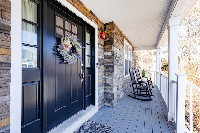 property entrance featuring a porch and stone siding