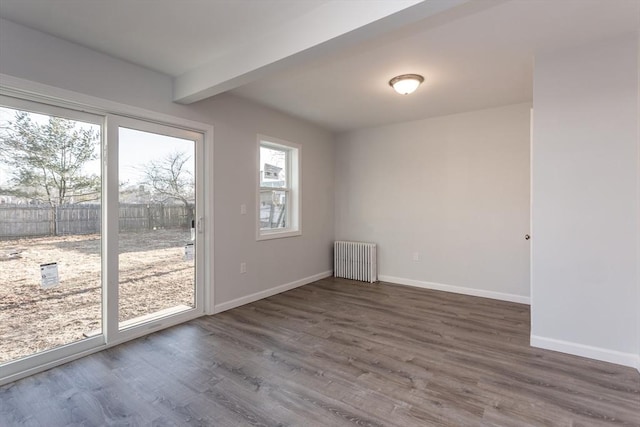 spare room featuring radiator, beamed ceiling, baseboards, and wood finished floors