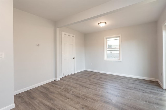 spare room with baseboards and wood finished floors