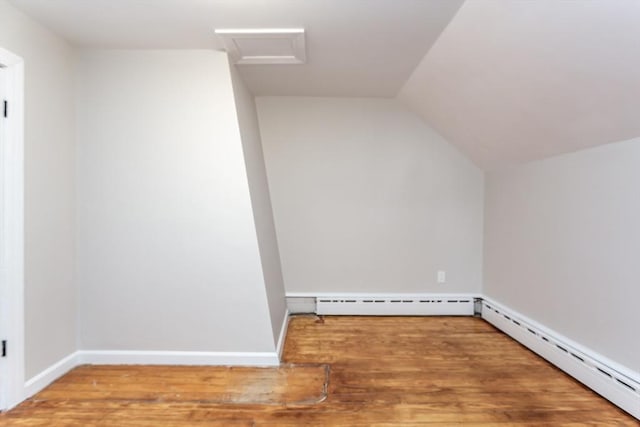 bonus room with a baseboard heating unit, wood finished floors, and attic access