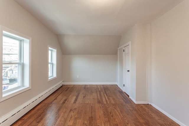 additional living space with vaulted ceiling, baseboard heating, wood finished floors, and baseboards