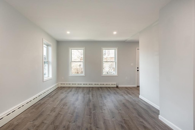 spare room with a baseboard heating unit, baseboard heating, wood finished floors, and baseboards