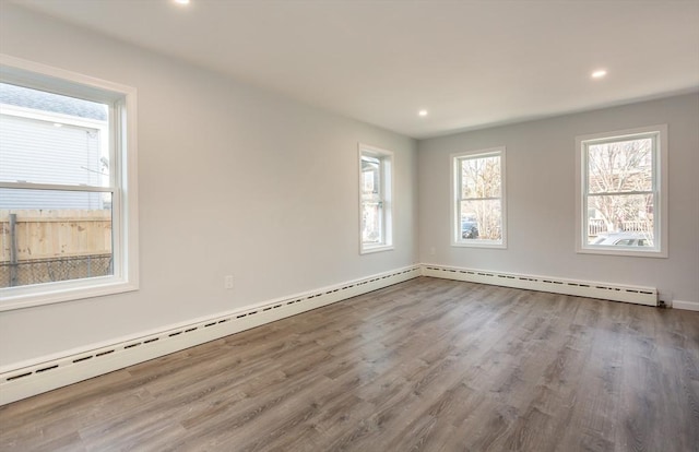 spare room with a baseboard radiator, wood finished floors, and recessed lighting