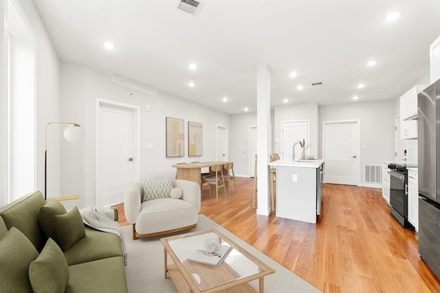 living area with recessed lighting, light wood-style flooring, and visible vents