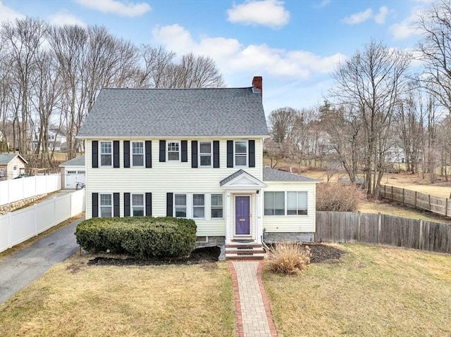 view of front of house featuring a chimney, fence, a front yard, and roof with shingles