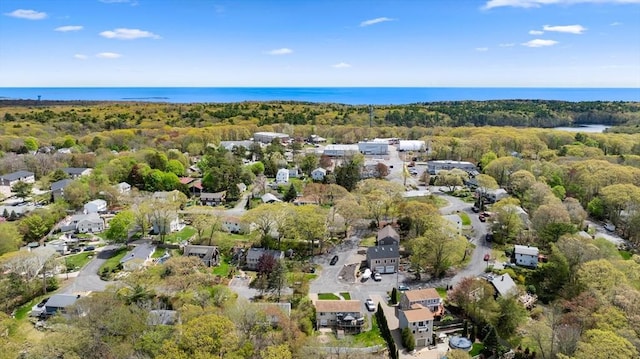 view of property location featuring a nearby body of water, a forest, and nearby suburban area